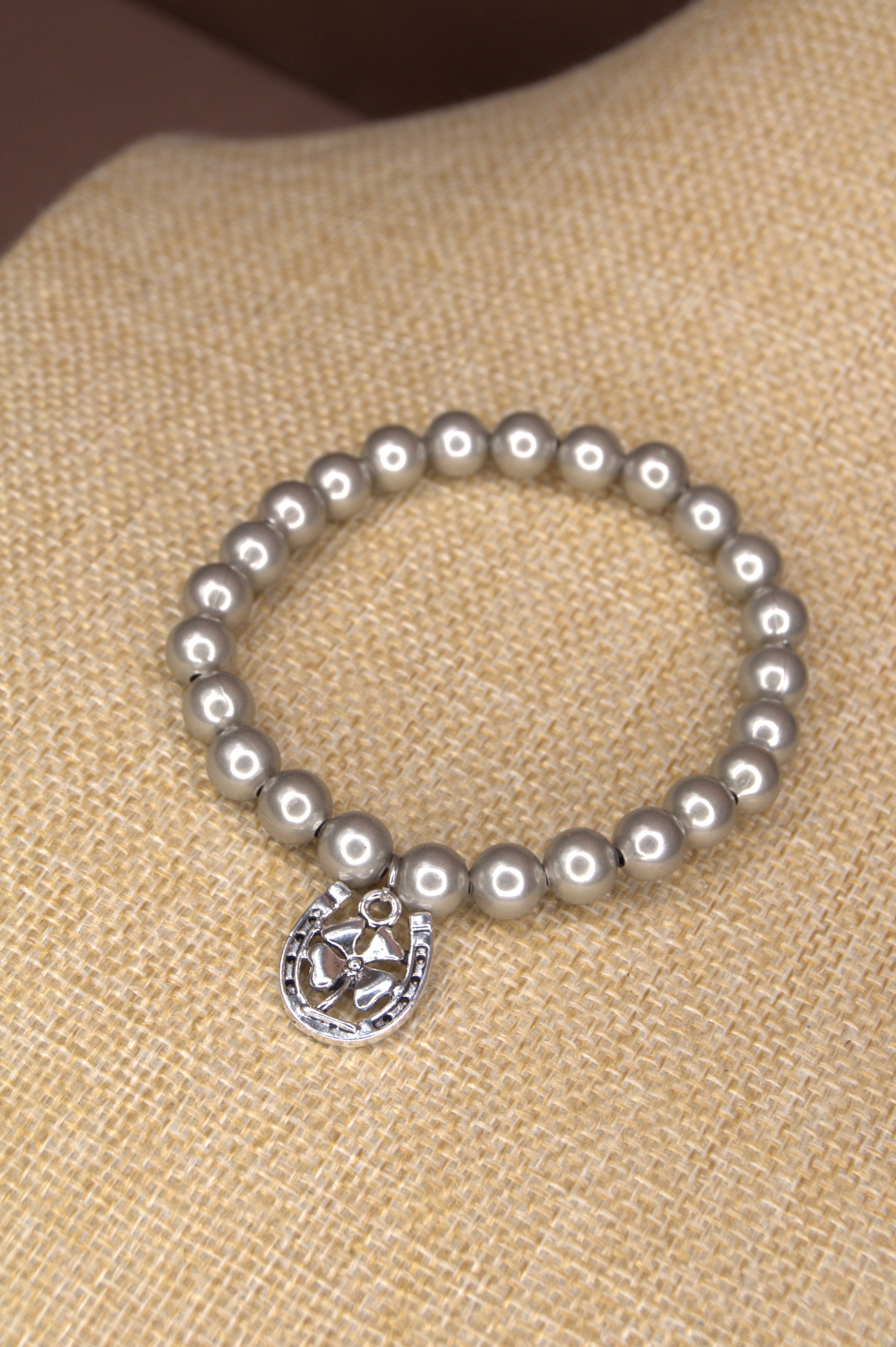 8mm silver metal bead stretch bracelet with a silver horseshoe and clover charm on the bracelet. 