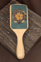 Wooden paddle brush with floral design on a wooden surface