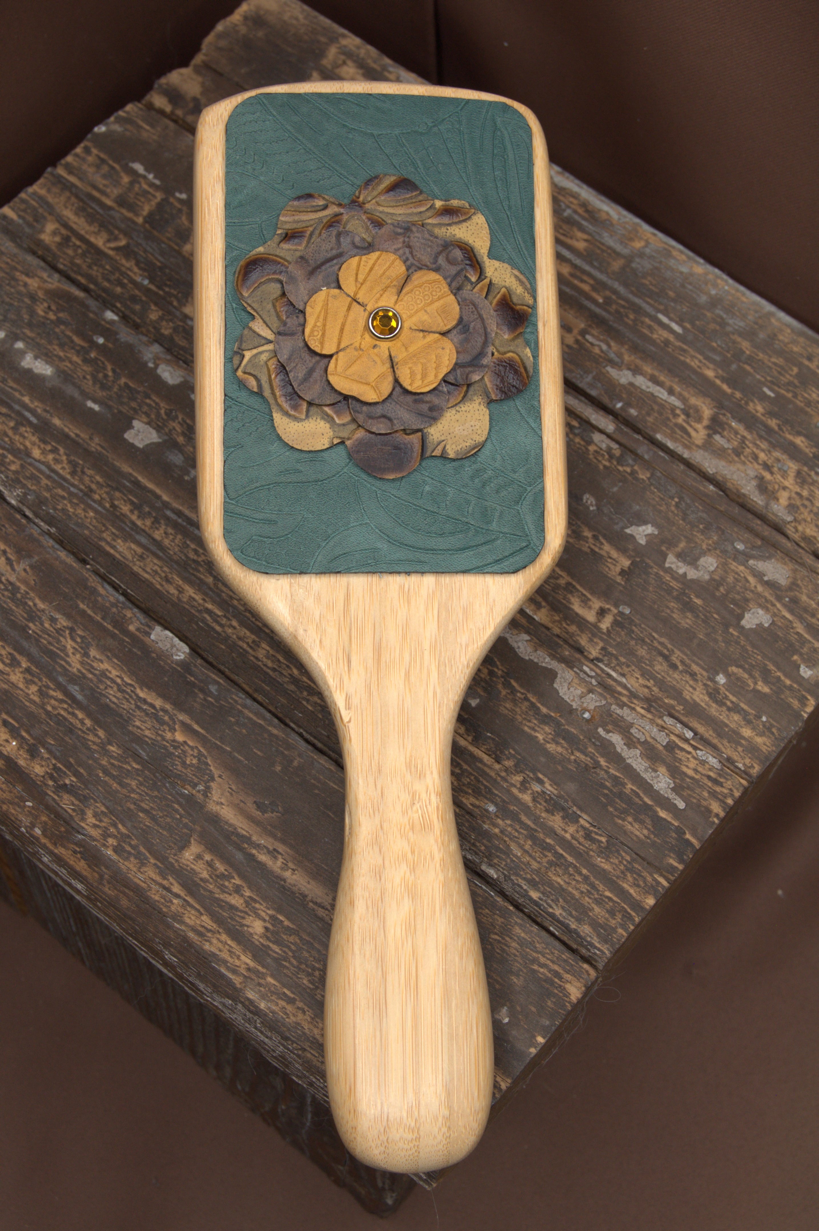 Wooden paddle brush with floral design on a wooden surface
