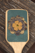 Leather accented hair brush with leather flower.