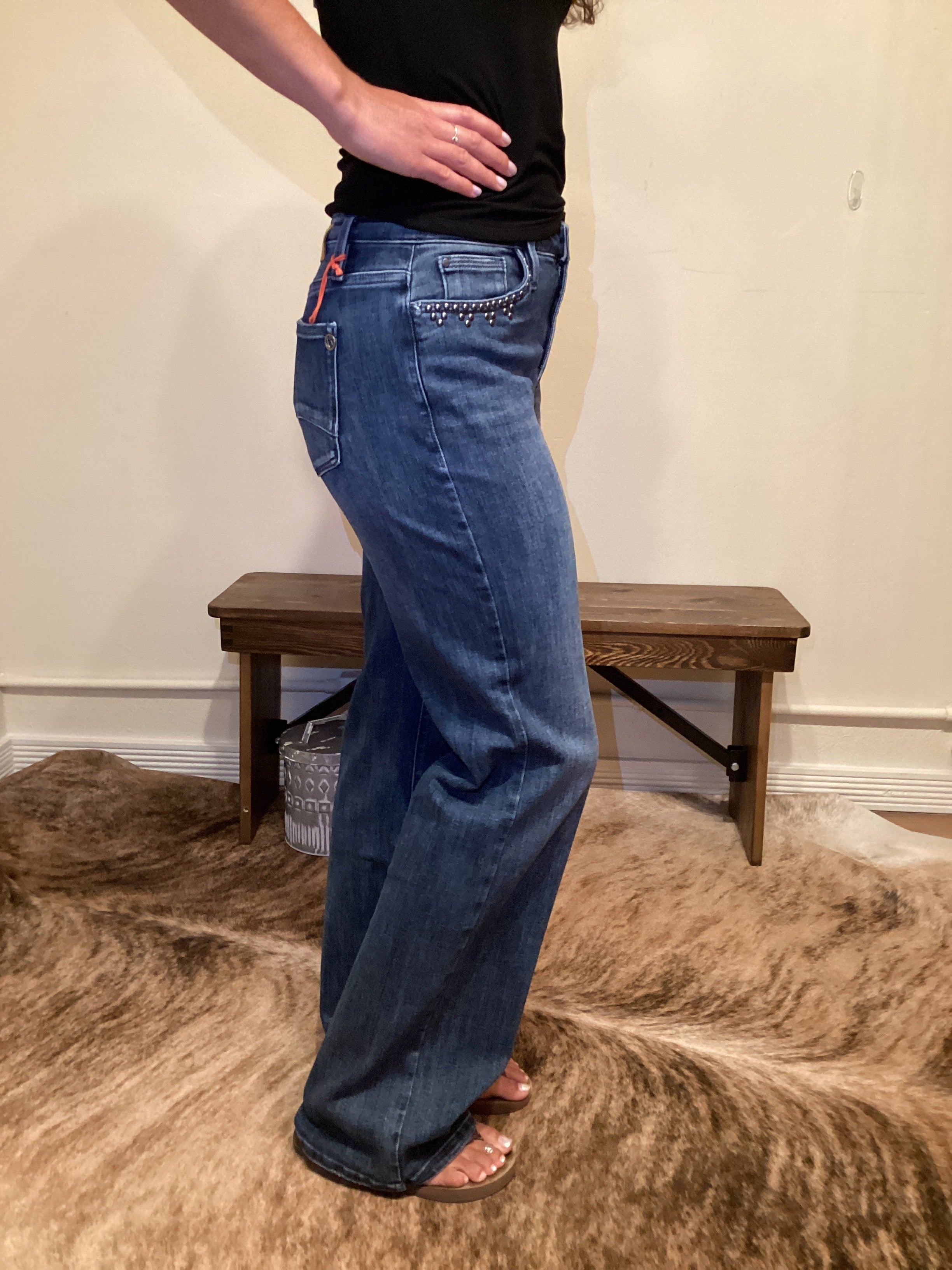 side view of Person wearing blue jeans with stud detailing on the edge of the front pockets