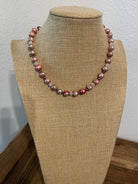 Necklace with pink dyed pearls and white crystals with silver bead accents on a beige mannequin.