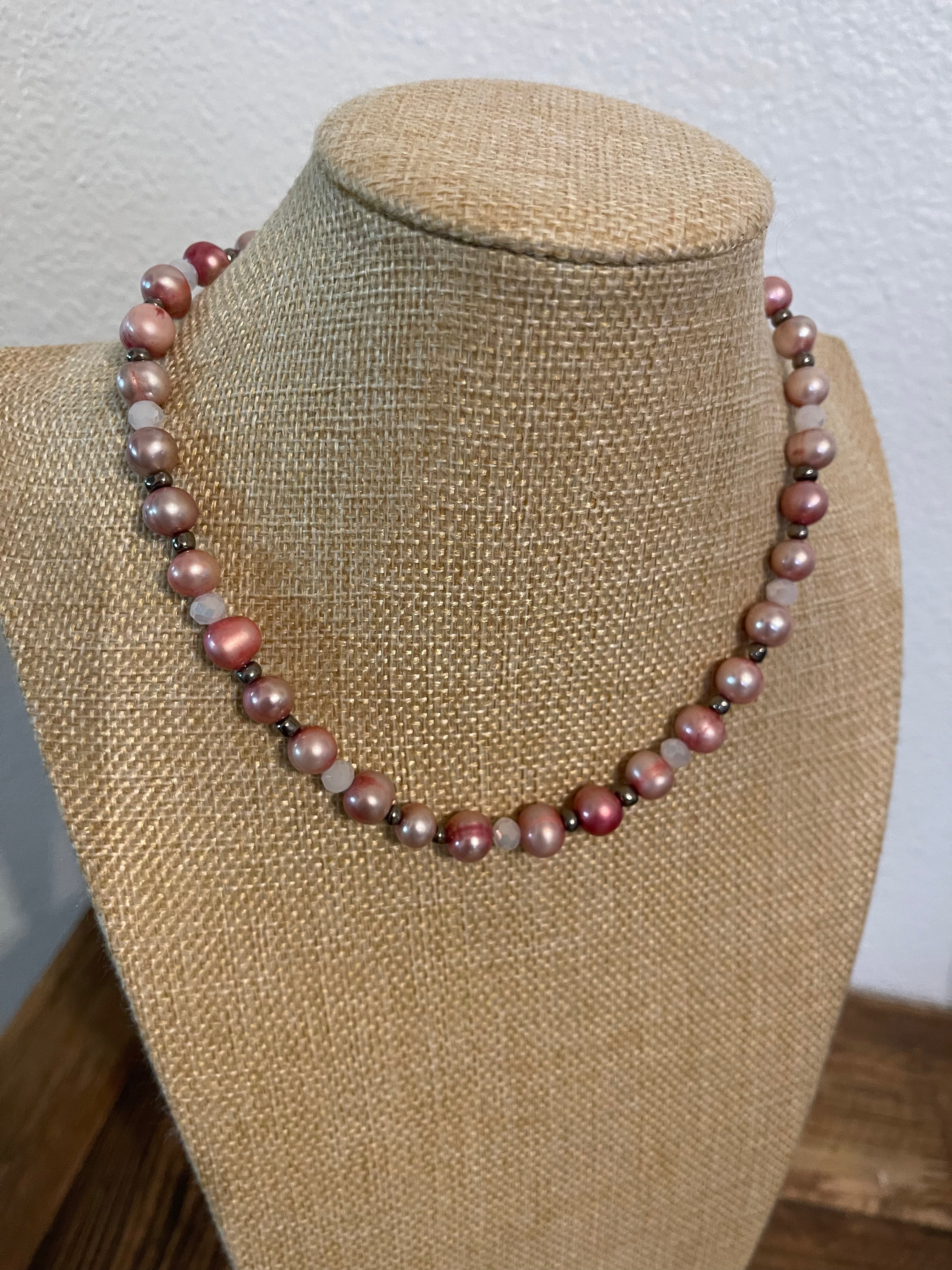 Necklace with pink dyed pearls and white crystals with silver bead accents on a beige mannequin.