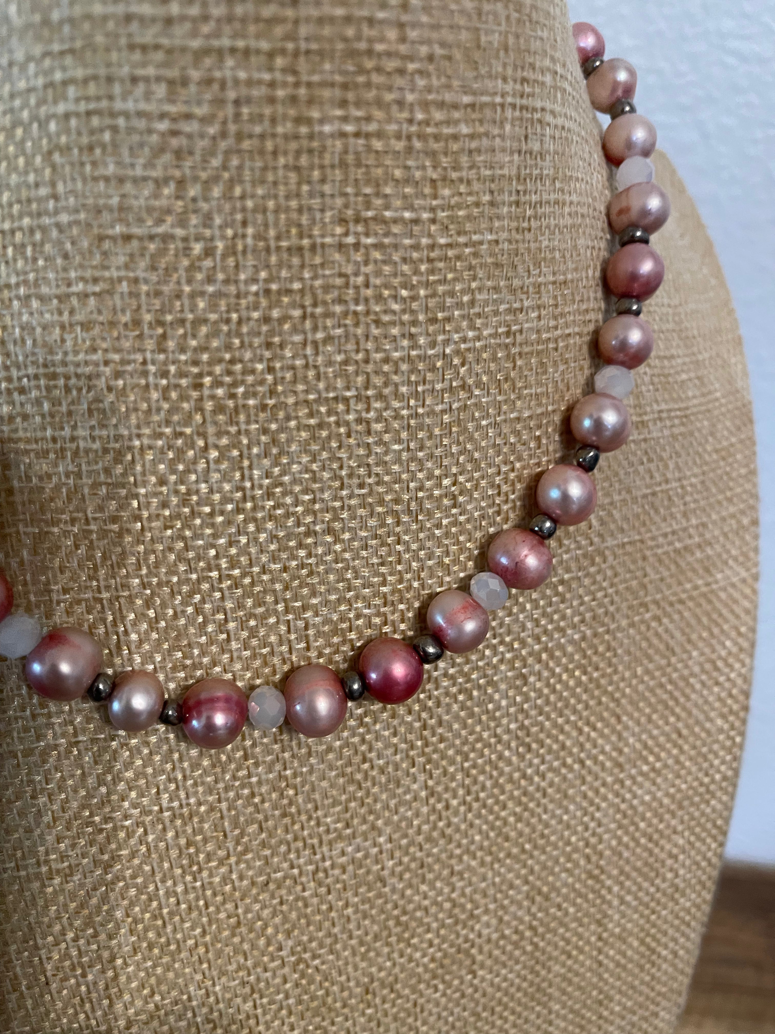 Necklace with pink dyed pearls and white crystals with silver bead accents on a beige mannequin.
