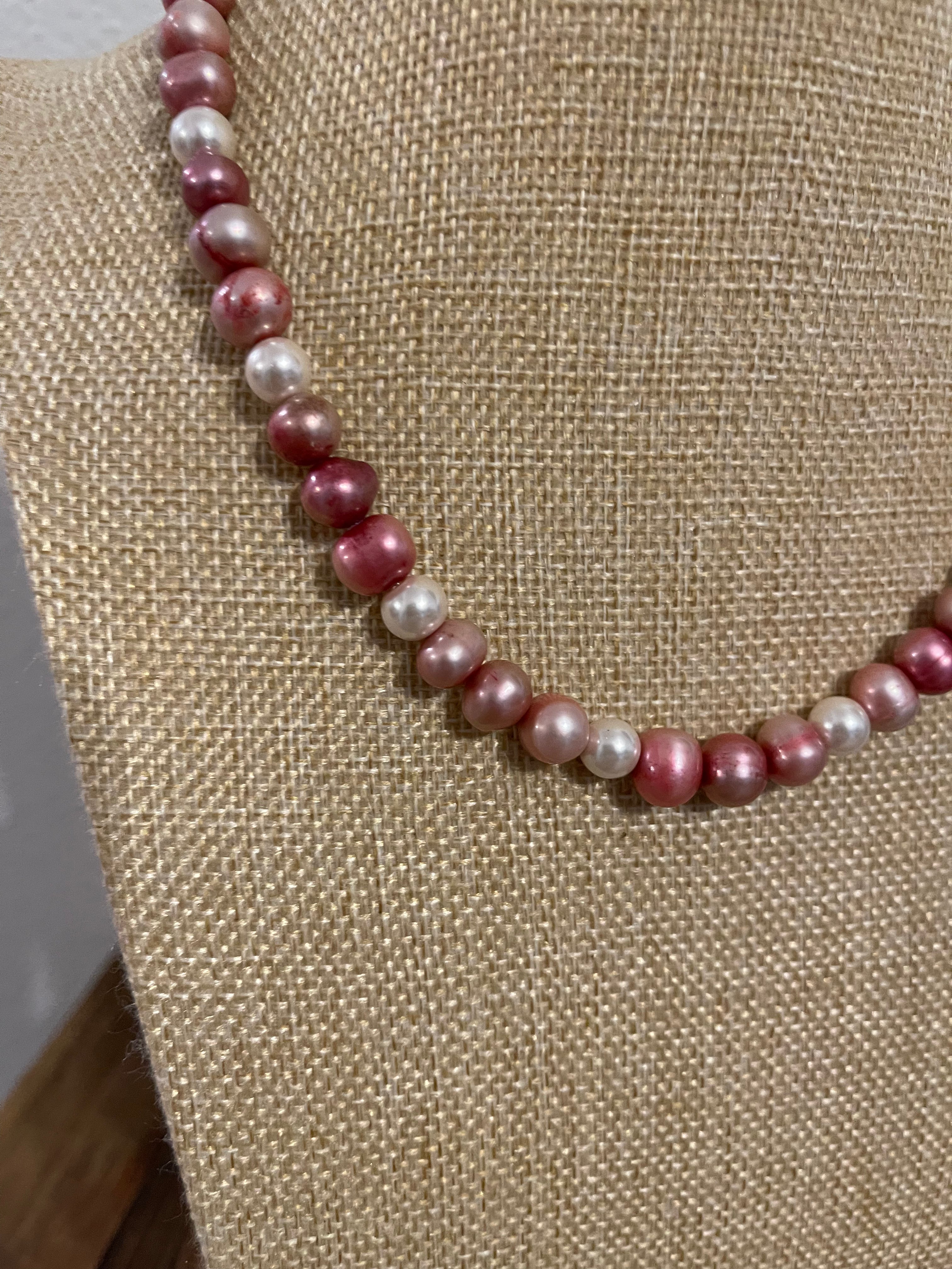 Necklace with pink and white pearls on a beige fabric background