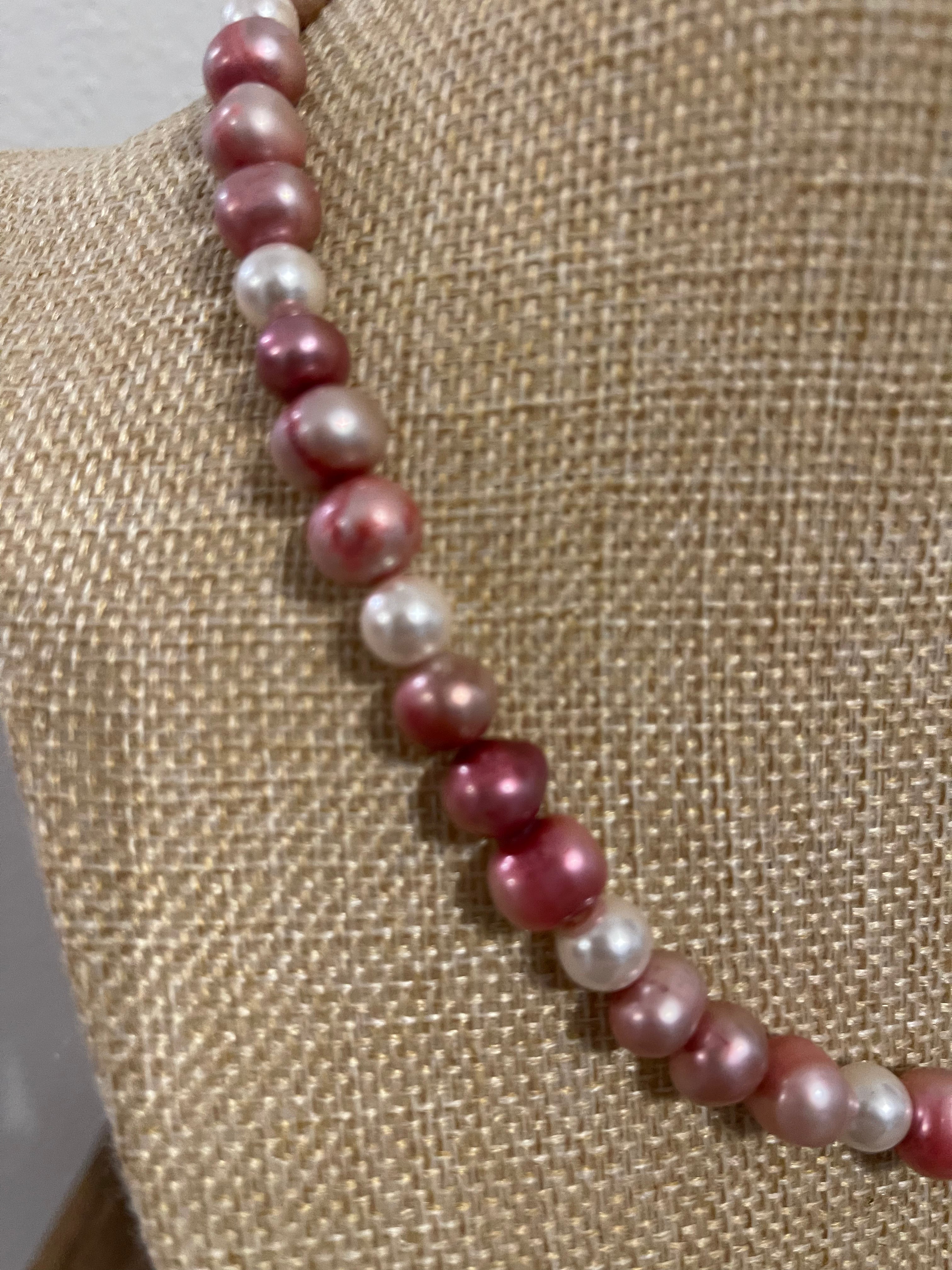 Necklace with pink and white pearls on a textured beige surface
