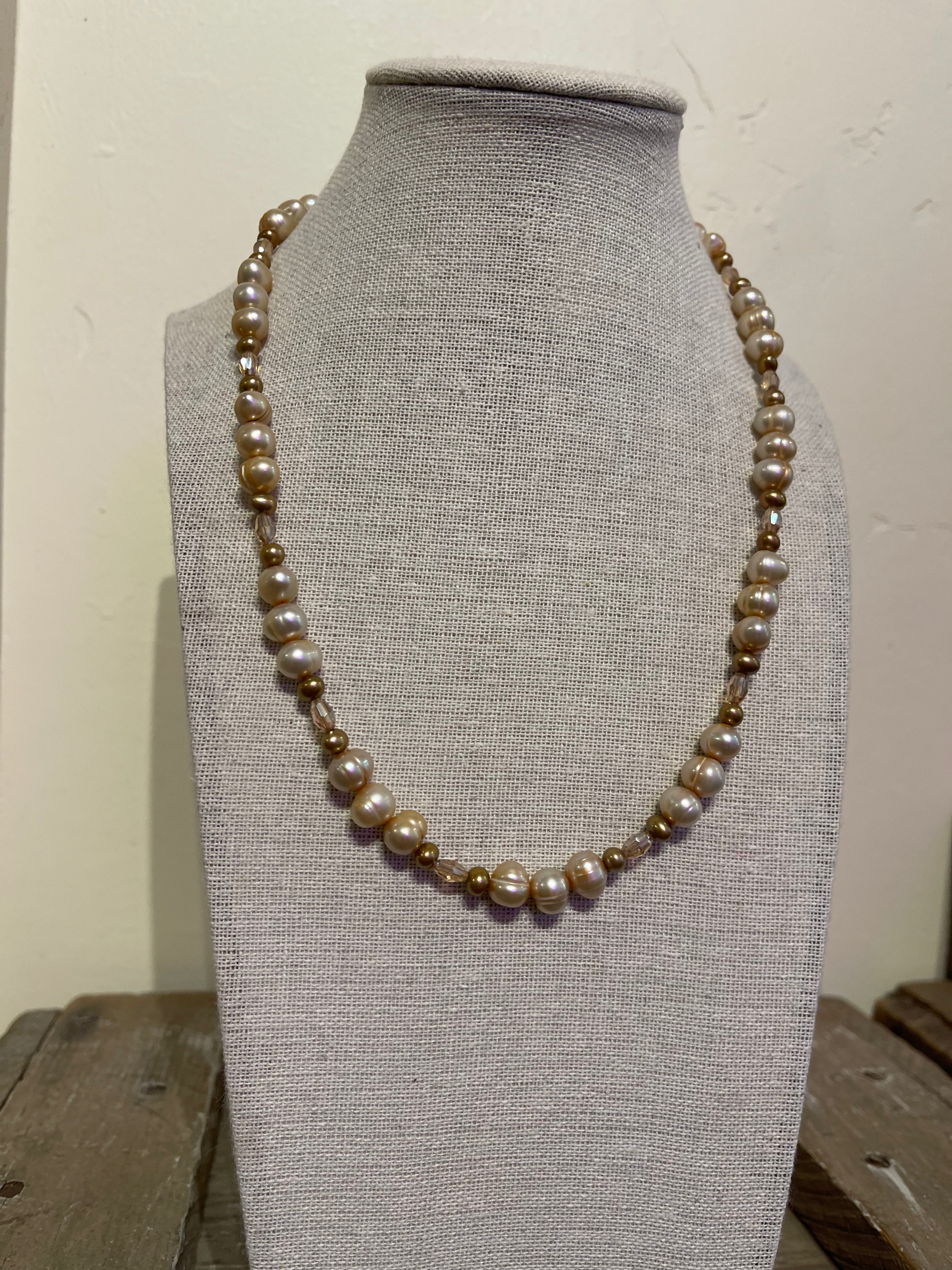 Pearl necklace on a gray mannequin bust against a white background