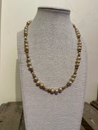 Pearl necklace on a gray mannequin bust against a white background