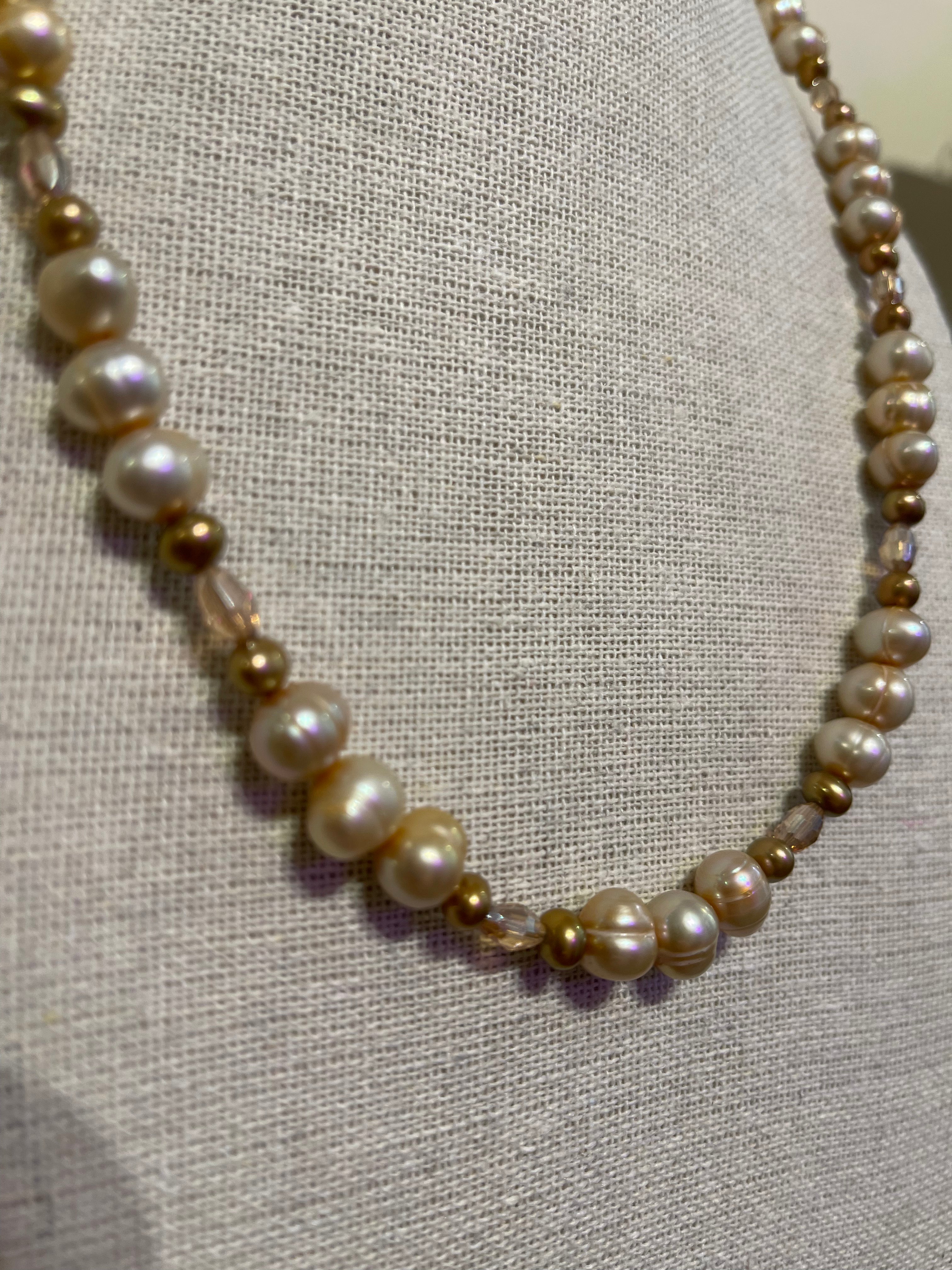 Necklace with pearls and gold beads on a textured fabric background