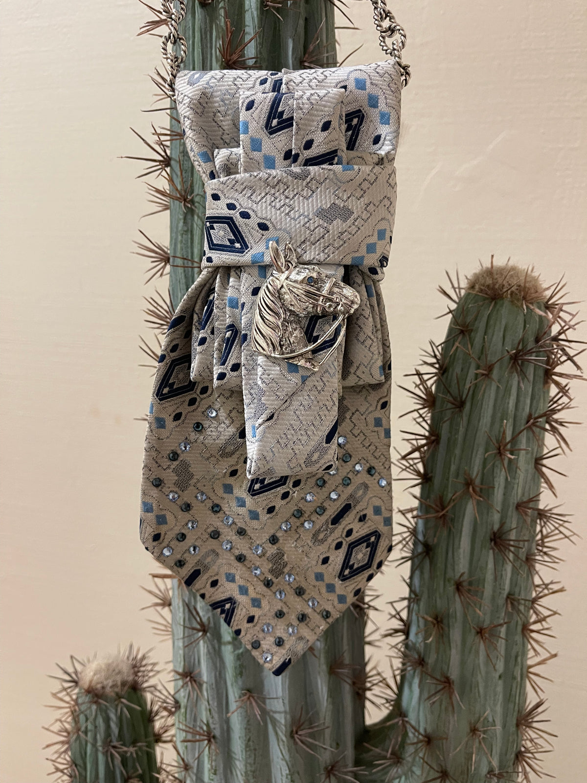 Handcrafted vintage tie necklace by Copper &amp; Lace Western Boutique featuring an authentic 1970s silver, navy, and blue patterned necktie with rhinestone embellishments, vintage silver horse head brooch, and ornate silver chain.