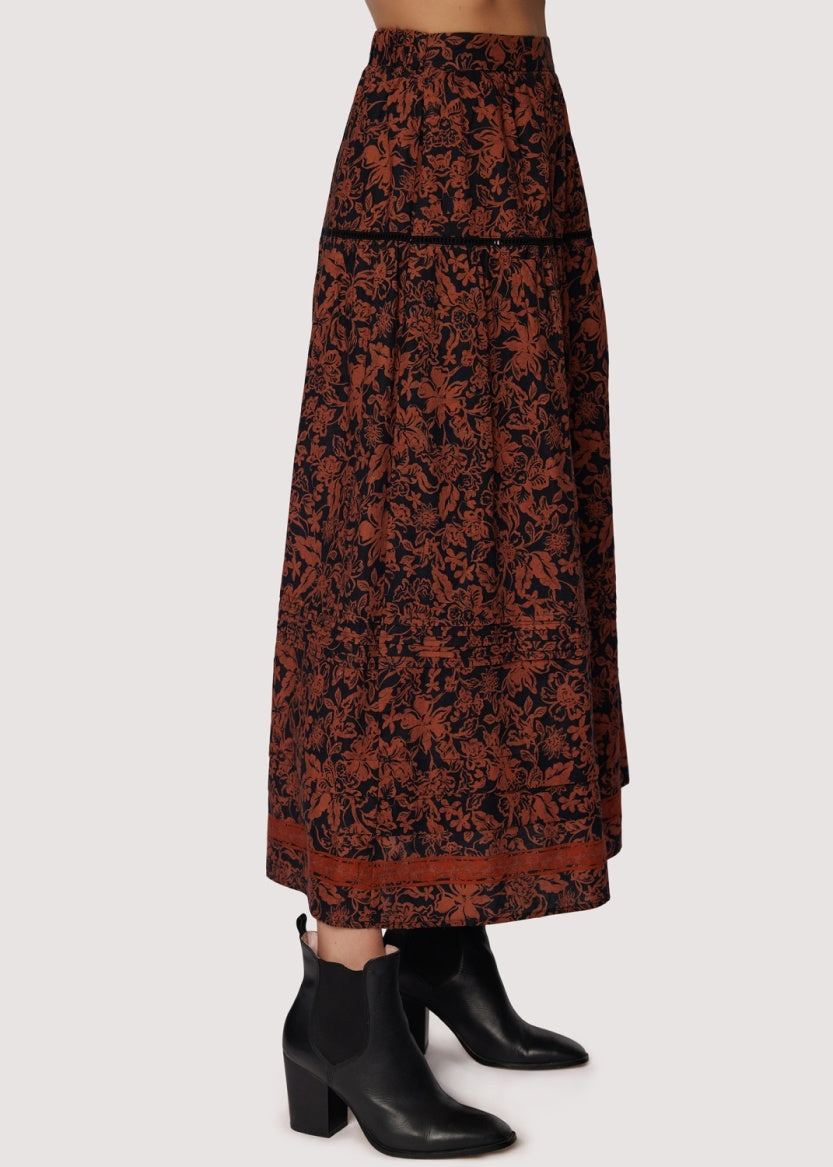 Long patterned skirt worn with black boots on a white background