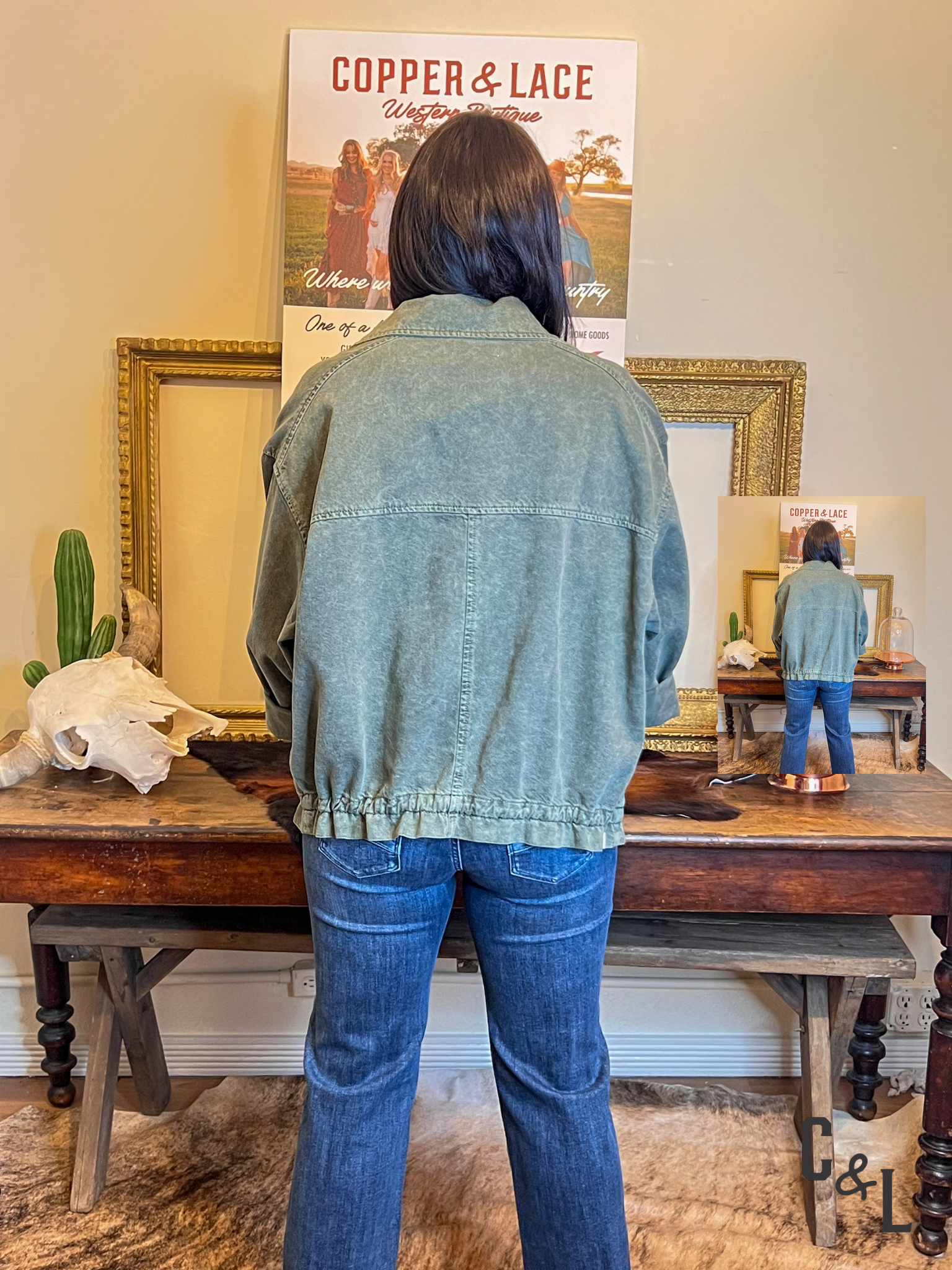 Person wearing a denim jacket and jeans standing in front of a mirror with a 'Copper & Lace' poster on the wall.