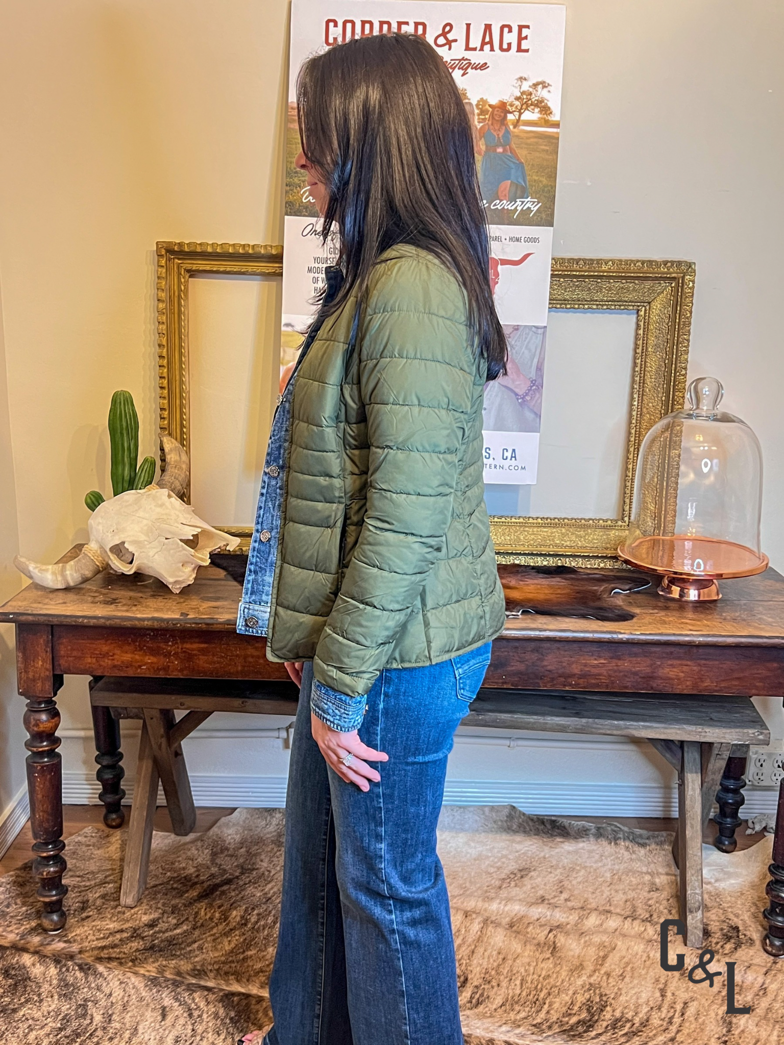 Person wearing a green puffer jacket standing in front of a table with decorative items.