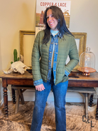 Woman wearing a green quilted jacket with denim blue trim on cuffs and front button area and collar