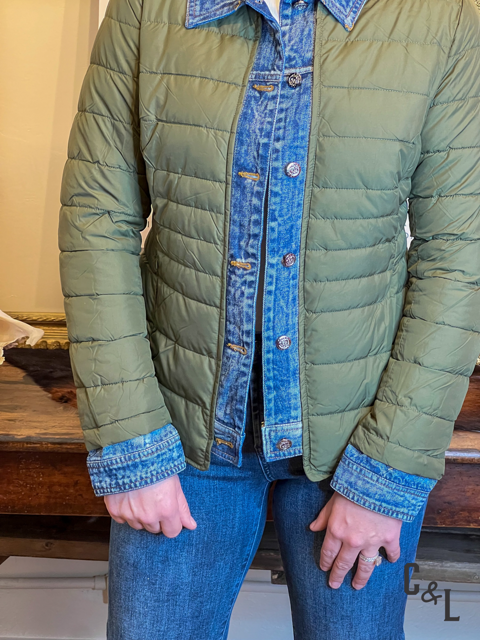 Green quilted jacket with denim collar and cuffs worn by a person indoors.