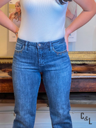 Person wearing blue jeans and a light blue top in an indoor setting with a blurred background