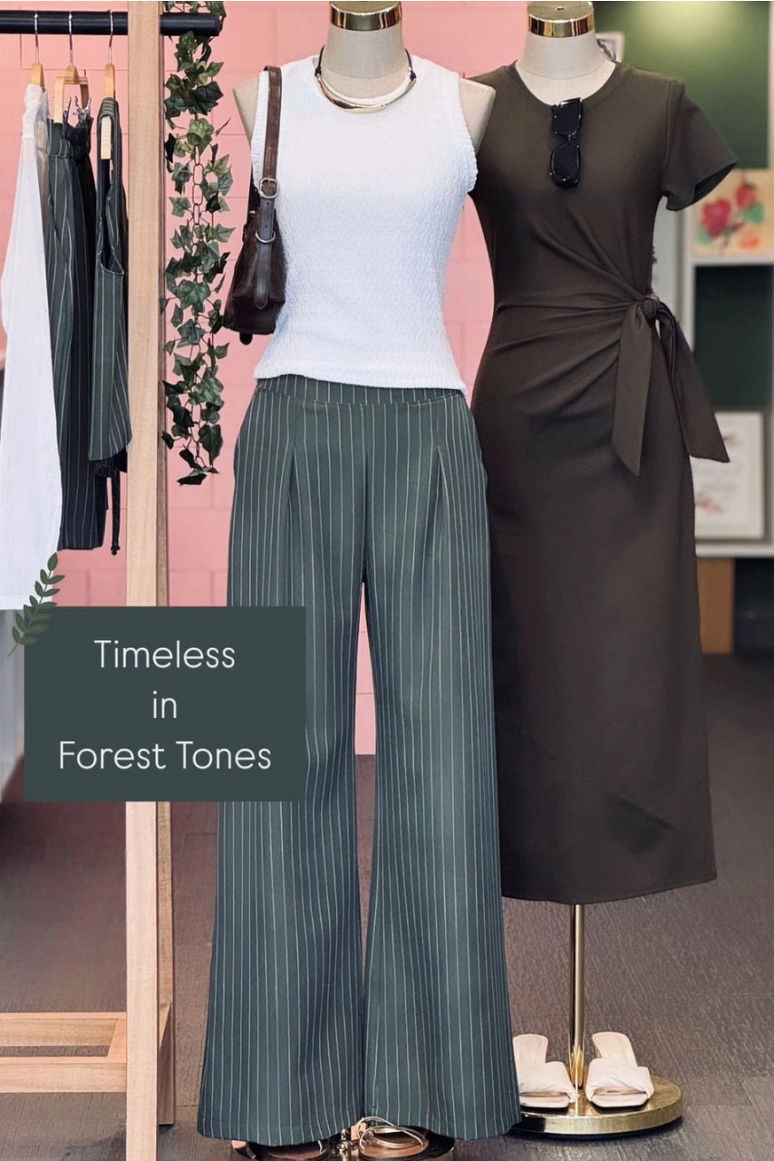 Mannequins wearing a white top, green wide leg pants, and a brown dress with text 'Timeless in Forest Tones'.