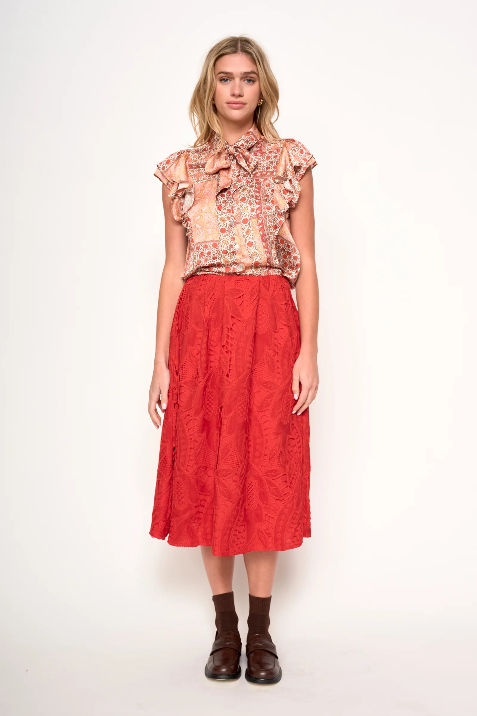 Woman wearing a floral blouse  in orange, rust and ivory satin 