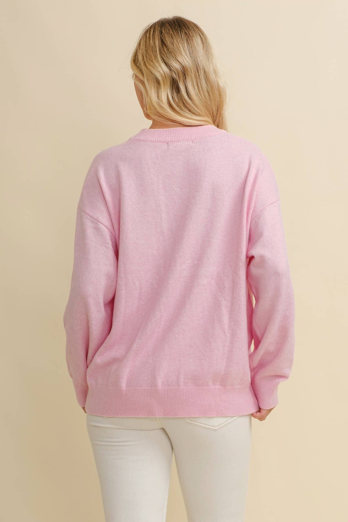 Person wearing a pink sweater against a beige background