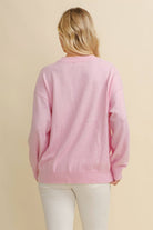 Person wearing a pink sweater against a beige background