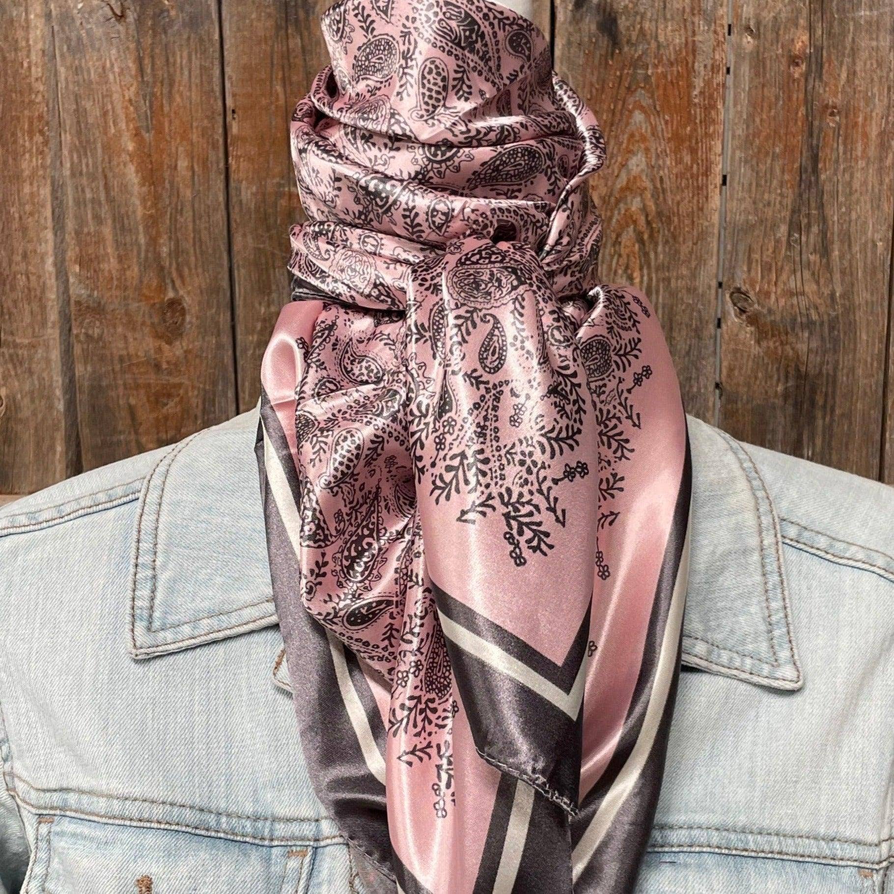 Person wearing a pink and grey patterned scarf with a wooden background