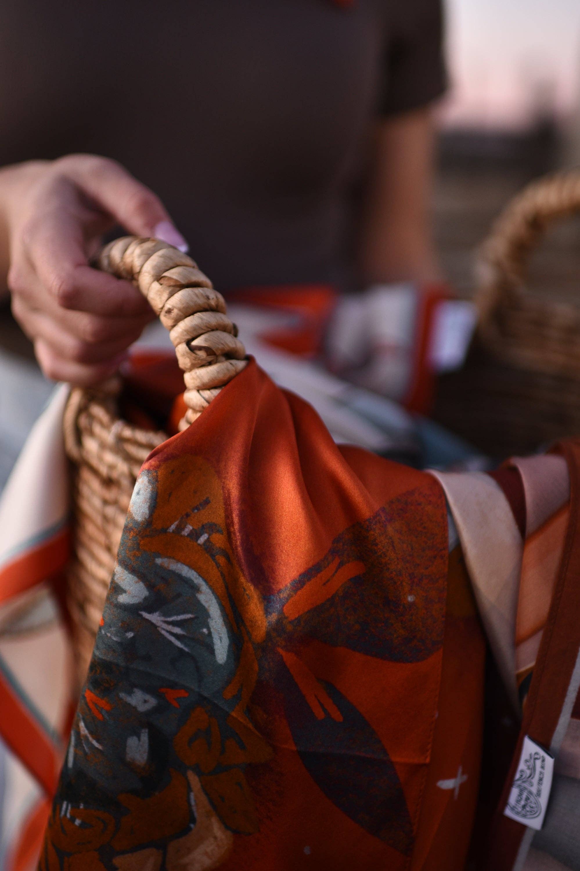 Person holding a woven basket with a red garment featuring black patterns.