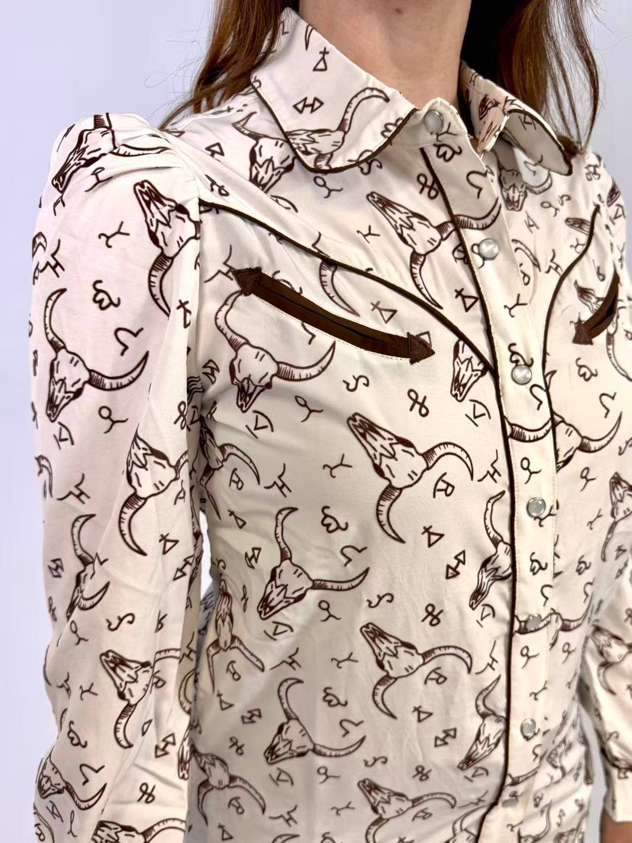Person wearing a patterned shirt with longhorn bull design on a light background