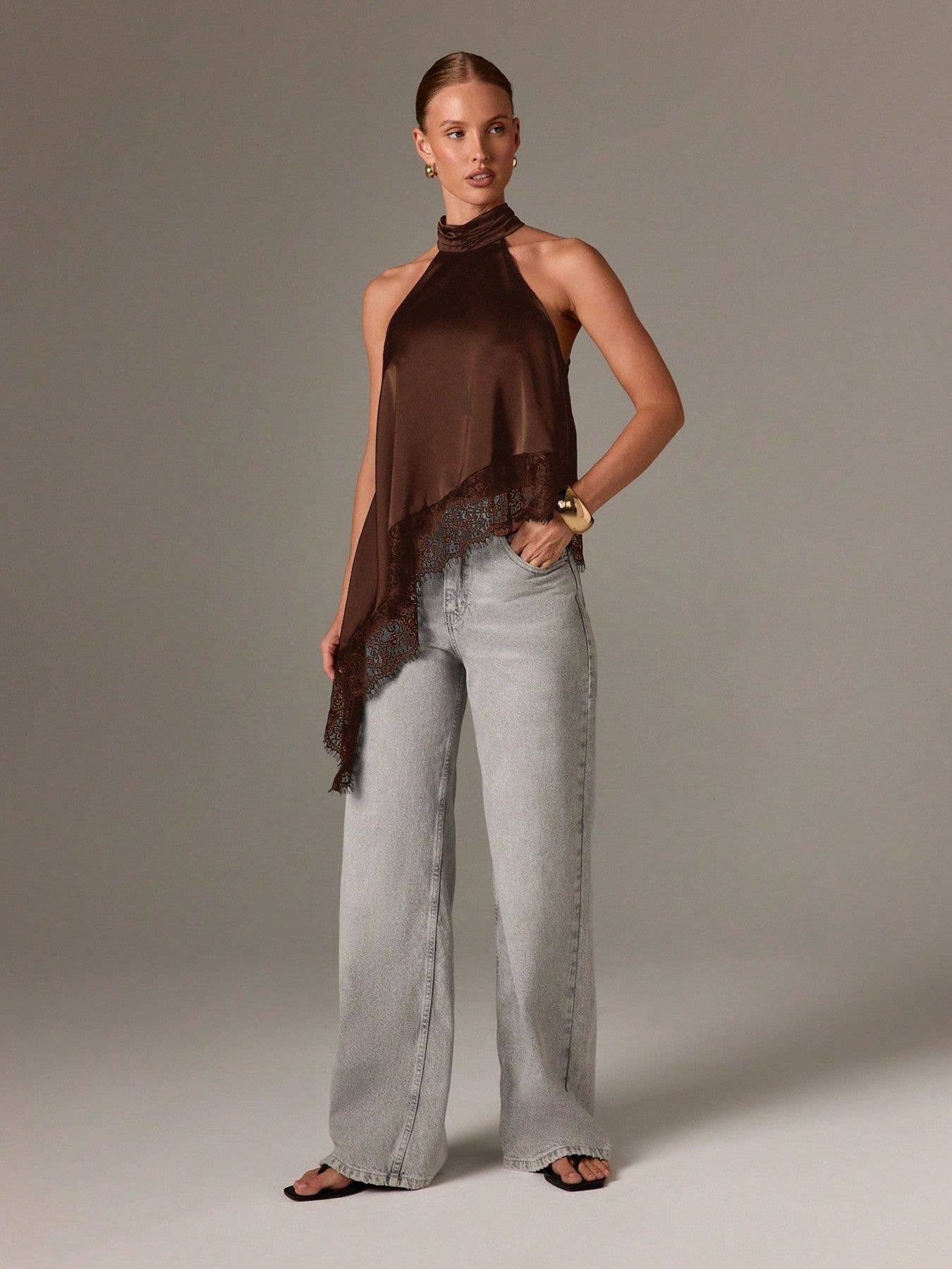 Woman wearing a brown halter top and light gray pants against a neutral background