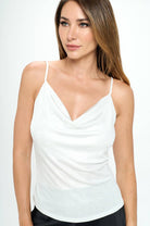 Woman wearing a white sleeveless top against a plain background