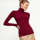 Woman wearing a maroon turtleneck sweater on a plain background