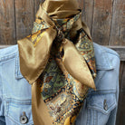 Patterned scarf draped over a denim jacket against a wooden background
