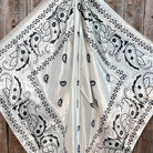 Black paisley pattern on a white fabric draped over a wooden surface