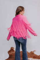 Person wearing a pink fringed jacket with a plain background