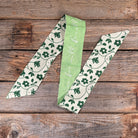 Three green and white patterned ribbons on a wooden surface