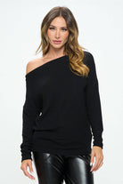 Woman wearing a black off-shoulder sweater on a white background