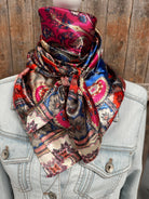 Colorful patterned scarf draped over a denim jacket against a wooden background