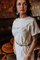 Woman wearing a white dress with floral patterns in an indoor setting