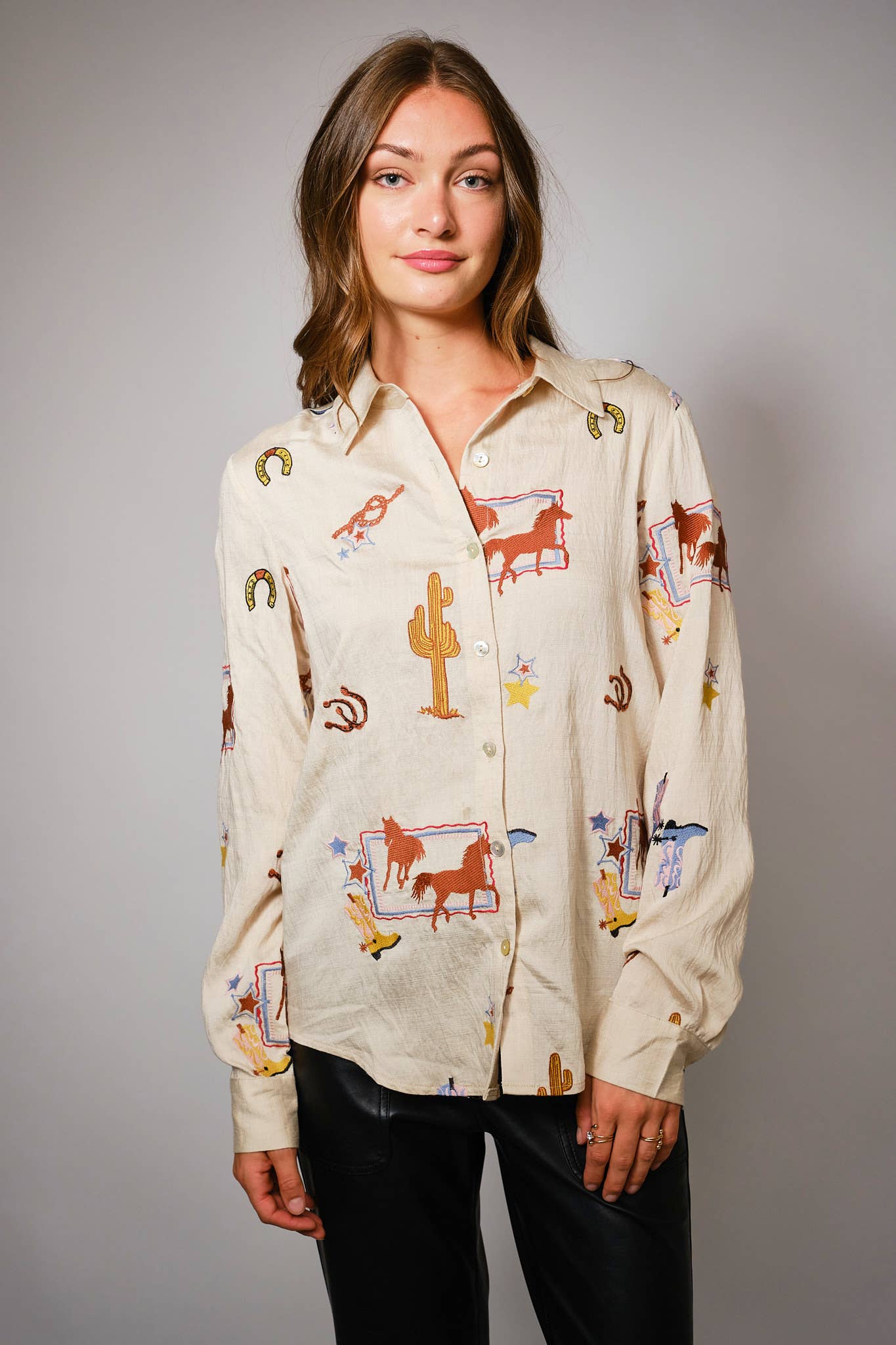 Woman wearing a  western patterned shirt with long sleeves against a plain background