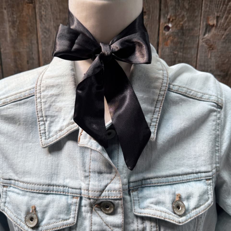 Denim jacket with a black bow tie against a wooden background