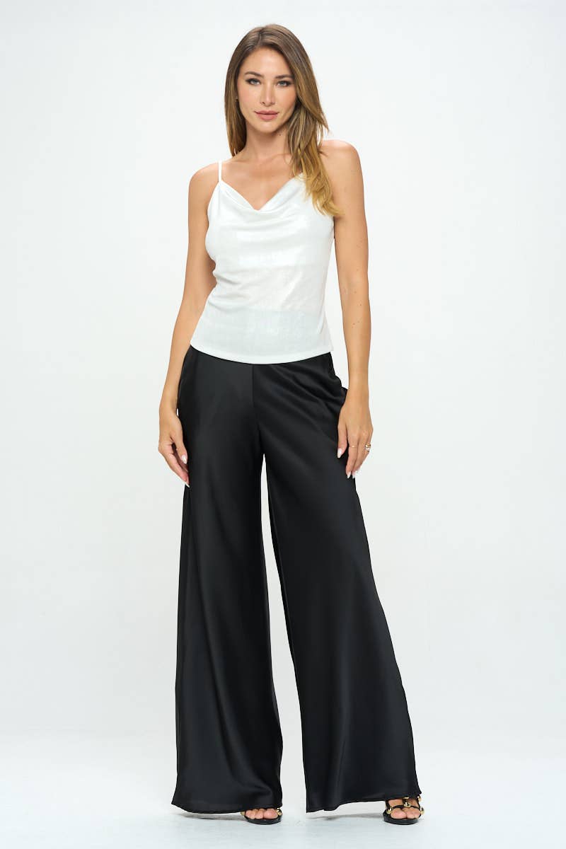 Woman wearing a white sleeveless top and black wide-leg pants on a white background