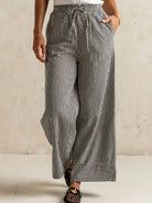 Person wearing black and white checkered pants against a beige wall.
