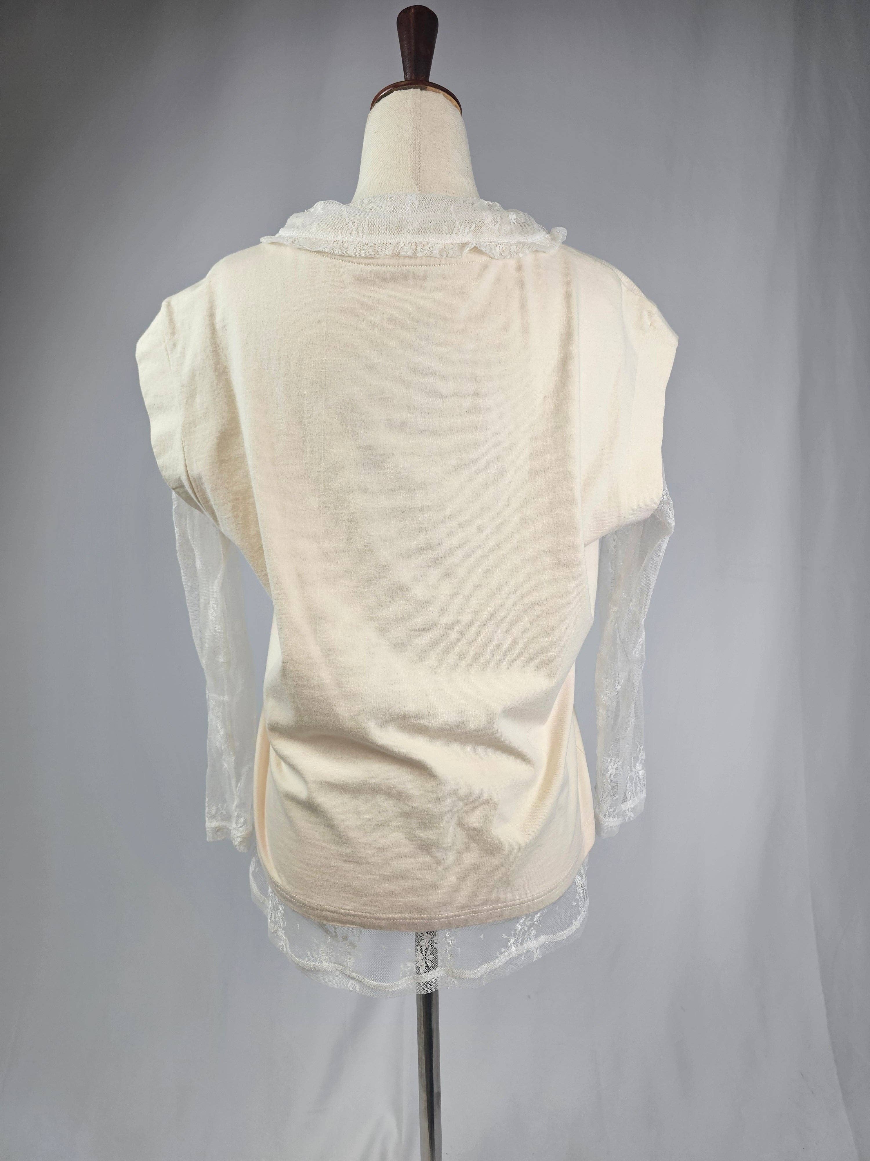 Mannequin wearing a cream-colored garment with sheer sleeves against a plain background