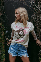 Woman wearing a graphic t-shirt with text and a graphic of a woman in a cowboy hat.