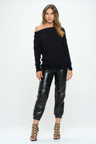 Woman wearing a black off-shoulder top and black leather pants on a white background